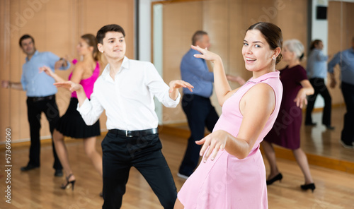 young couple enthusiastically dancing social latin cha-cha-cha dance in dance studio