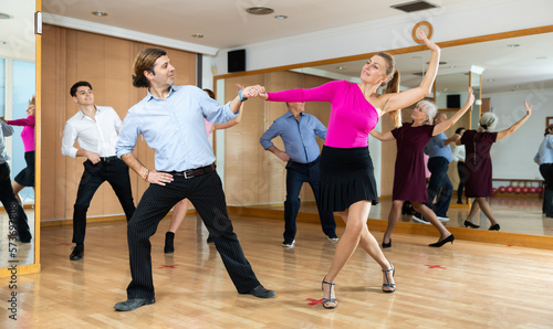 Pair of cheerful adult amateur dancers practicing vigorous playful swing in dance class. Social dancing concept