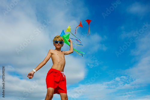 Smiling in sunglasses boy stand holding many colorful kites