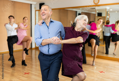 Active elderly pair practicing Latino dance in training hall during dancing-classes. Pairs training ballroom dance