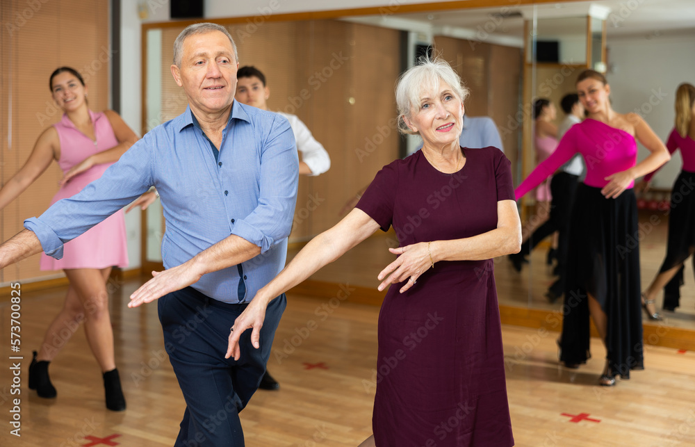 Spirited old pair training Latino dance during workout session. Pairs training ballroom dance in hall