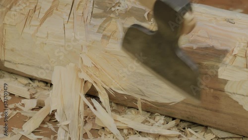 Lumberjack cutting large log with axe at workshop - close up. Craftsmanship, revival and handwork concept
