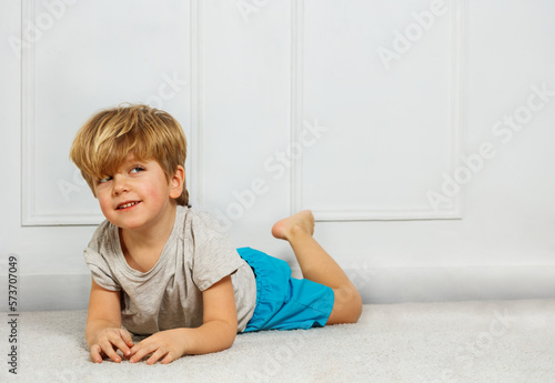 Caucasian boy lay happy smiling on white carpet at home