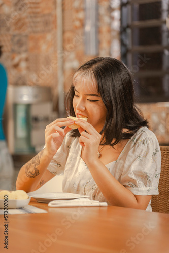 Young asian lady having a cheese bread on the breakfast at the kitchen.