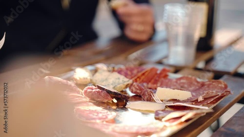 Traditional Italian aperitif in local restaurant of traditional cuisine, people tasting slices of high quality prosciutto di parma, salami, parmigiano cheese and typical gorgonzola, rustic snacks and