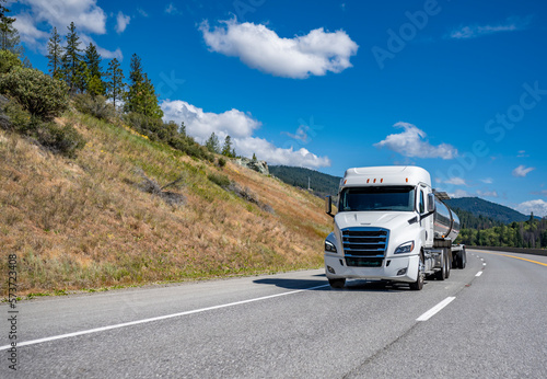 Wallpaper Mural Long haul low cab profile white big rig semi truck transporting liquid cargo in tank semi trailer driving on the winding mountain road Torontodigital.ca