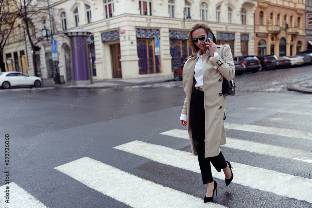 Woman in trendy outfits crosses road against backdrop of city buildings. High quality photo Woman in trendy outfits crosses road against backdrop of city buildings. High quality photo