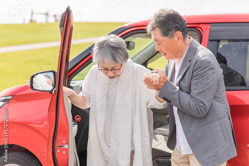 自動車から降りる高齢者女性と介助する男性（移乗）
 photo