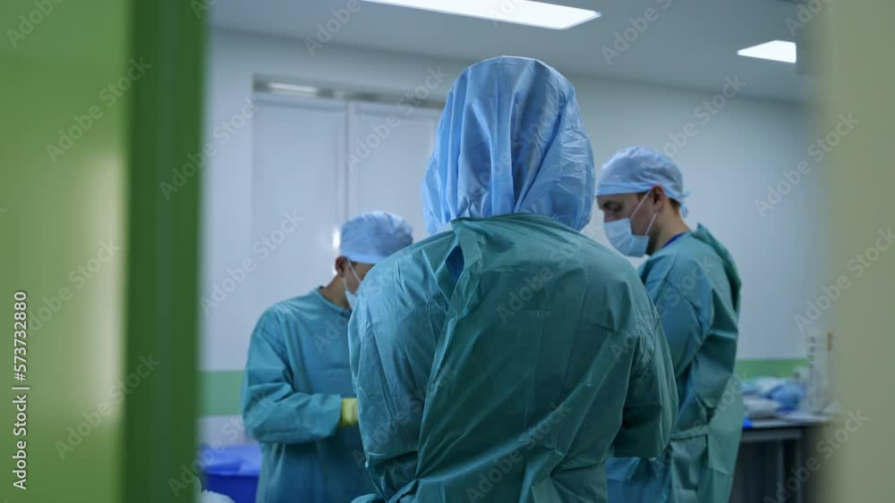 Male team of surgeons getting ready for operation. Professionals put on latex gloves in preoperative room. Male team of surgeons getting ready for operation. Professionals put on latex gloves in preoperative room.