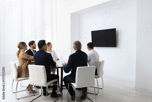 Business conference. Group of people watching presentation on tv screen in meeting room