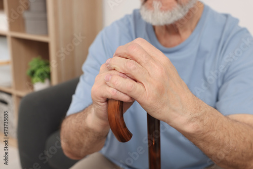 Senior man with walking cane at home, closeup