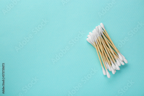 Many wooden cotton buds on turquoise background  flat lay. Space for text