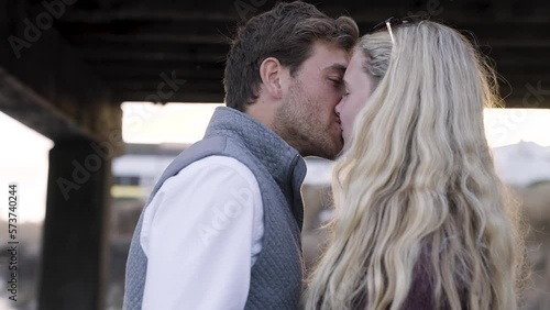 Happy Preppy Romantic Young White Couple during Sunset Golden Hour by the Ocean - medium shot of kissing photo