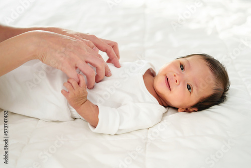 mother and her newborn baby lying and playing on bed