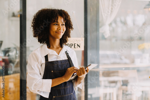 Startup successful small business owner sme beauty girl stand with tablet smartphone in coffee shop restaurant. Portrait of asian tan woman barista cafe owner. SME entrepreneur seller business concept