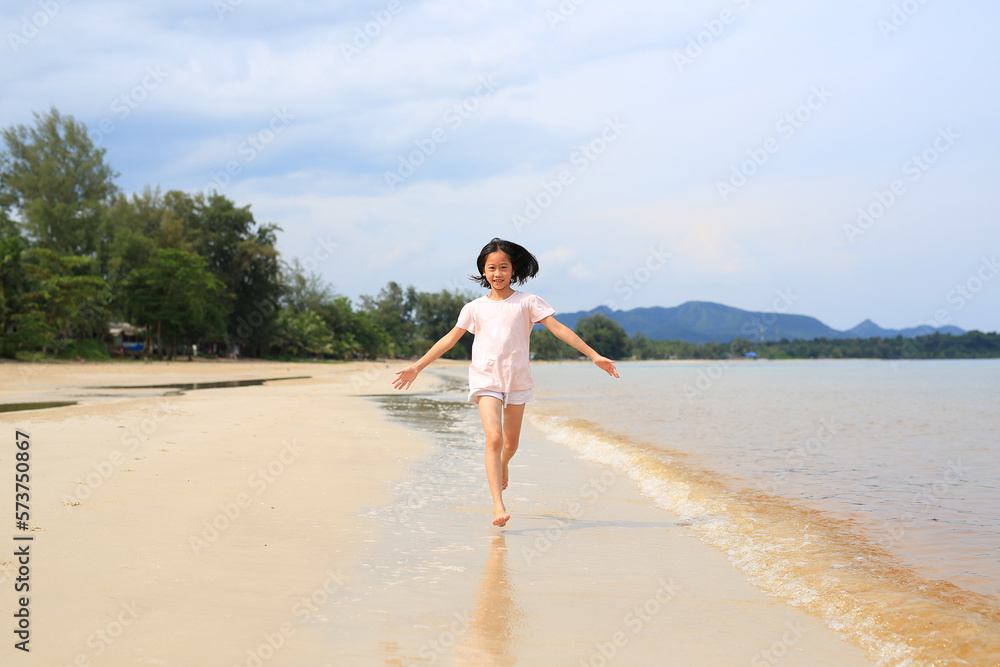 Cheerful Asian young girl child having fun running on tropical sand beach Cheerful Asian young girl child having fun running on tropical sand beach