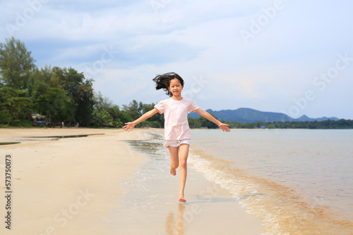 Asian young girl kid having fun running on tropical sand beach