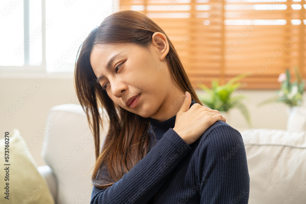 Body muscles stiff problem, asian young attractive woman, girl pain with back pain ache from work, holding massaging rubbing shoulder hurt or sore, painful sitting on sofa at home. Healthcare people. Body muscles stiff problem, asian young attractive woman, girl pain with back pain ache from work, holding massaging rubbing shoulder hurt or sore, painful sitting on sofa at home. Healthcare people.