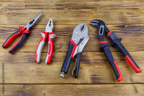 Set of different pliers on wooden background. Top view photo