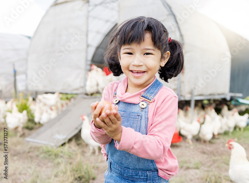 Portrait, Asian girl and farm for agriculture, chicken and happiness on holiday, vacation and holding eggs. Face, female child or kid in Japan, farming and sustainability with animals and countryside photo