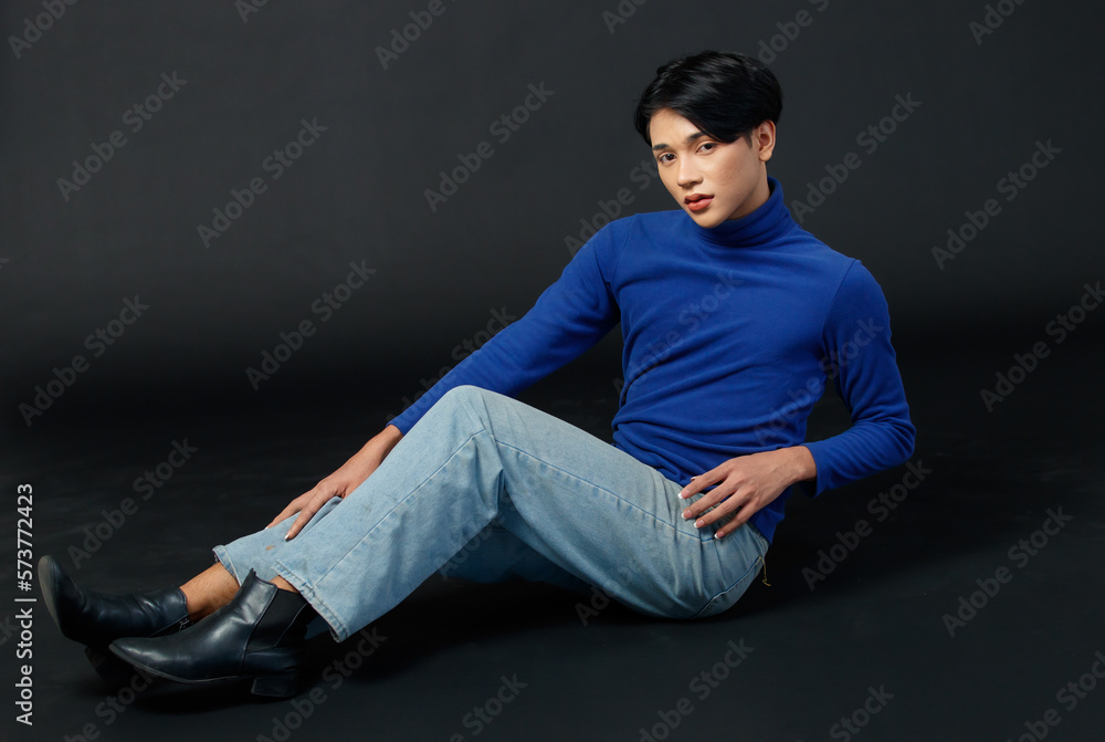 Portrait studio closeup full body shot of Asian young sexy luxury glamour slim fashionable LGBTQ gay male model in turtleneck long sleeve shirt jeans sitting holding leg up posing on black background Portrait studio closeup full body shot of Asian young sexy luxury glamour slim fashionable LGBTQ gay male model in turtleneck long sleeve shirt jeans sitting holding leg up posing on black background