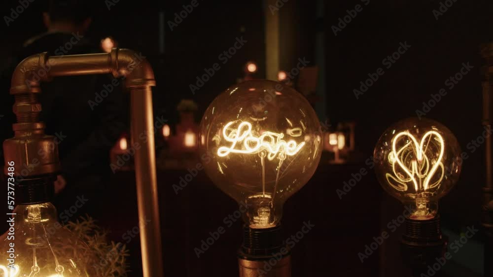 Artistic Incandescent light bulb with love inscribed in the filament. Designed with Love aesthetic. Shot in slow motion, 23.98 fps. Artistic Incandescent light bulb with love inscribed in the filament. Designed with Love aesthetic. Shot in slow motion, 23.98 fps.