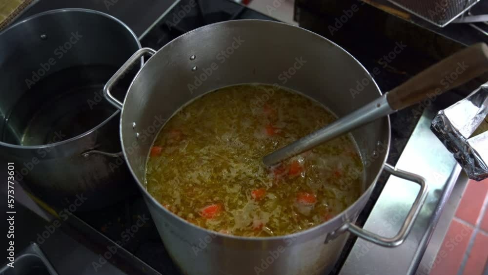 Chef adding blocks of Japanese curry roux into a big stock pot on stovetop, full of potatoes, carrots and onions, top down view. Chef adding blocks of Japanese curry roux into a big stock pot on stovetop, full of potatoes, carrots and onions, top down view.