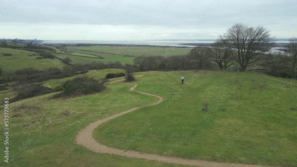 Mountain biker riding over hill approaching rocky trail at Hadleigh Park, drone Mountain biker riding over hill approaching rocky trail at Hadleigh Park, drone