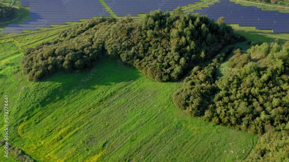 Aerial: Panoramic reveal shot of solar panels in green, grassy field Aerial: Panoramic reveal shot of solar panels in green, grassy field