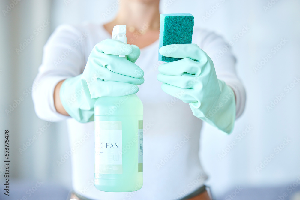 Fototapeta premium Woman, hands and detergent for housekeeping, cleaning or disinfect with latex gloves in sanitary home. Hand of female cleaner holding sanitizer bottle and sponge for domestic work or clean hygiene