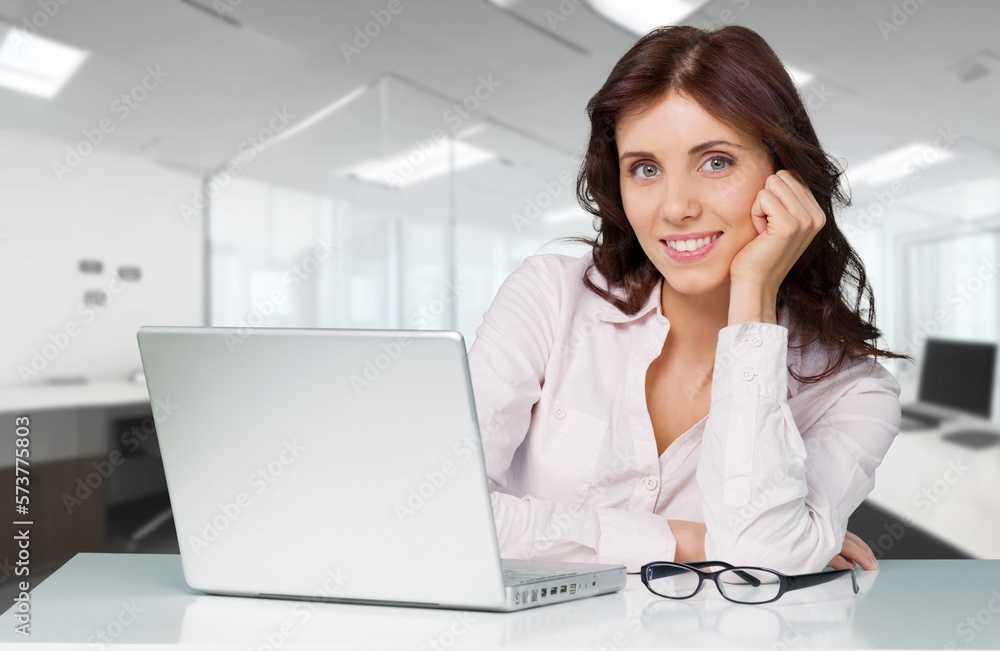 Young woman sitting and working on laptop in modern office. Young woman sitting and working on laptop in modern office.