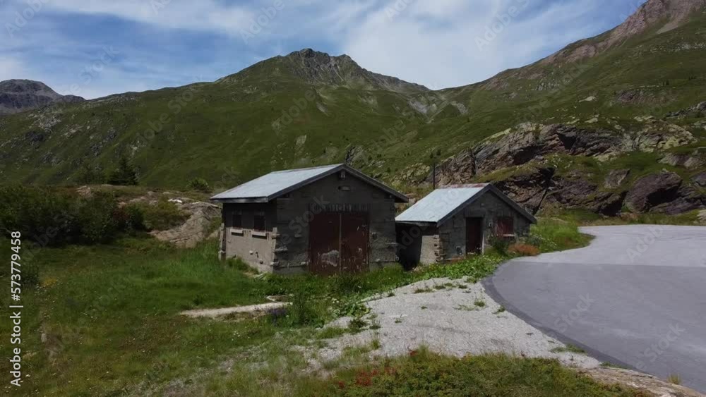 Tiny concrete homes in mountains of Switzerland, near road, aerial fly away view Tiny concrete homes in mountains of Switzerland, near road, aerial fly away view