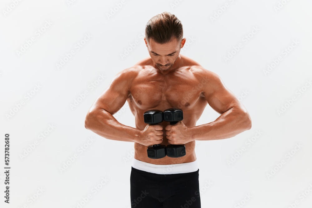 Man athletic body bodybuilder posing with dumbbells with naked torso abs full-length in the background, fitness class. Advertising, sports, active lifestyle, competition, challenge concept. Man athletic body bodybuilder posing with dumbbells with naked torso abs full-length in the background, fitness class. Advertising, sports, active lifestyle, competition, challenge concept.