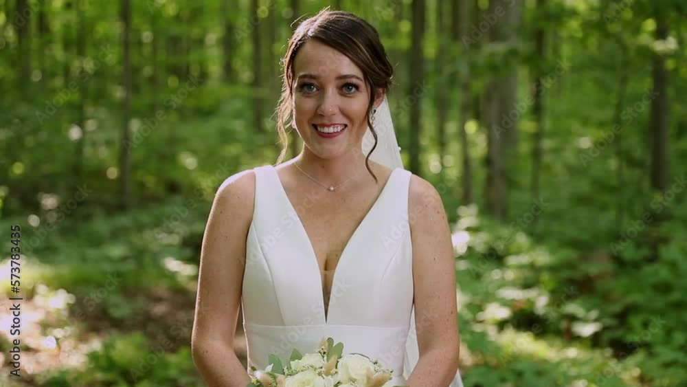 Bride Smiles While Holding Bouquet In A Forest On Her Wedding Day. Bride Smiles While Holding Bouquet In A Forest On Her Wedding Day.