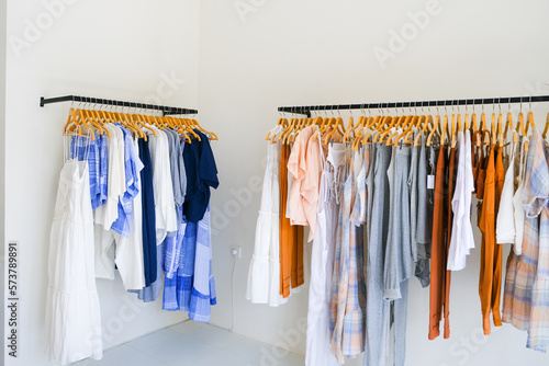 Two Racks of summer collection of natural clothes on hangers in retail fashion shop.