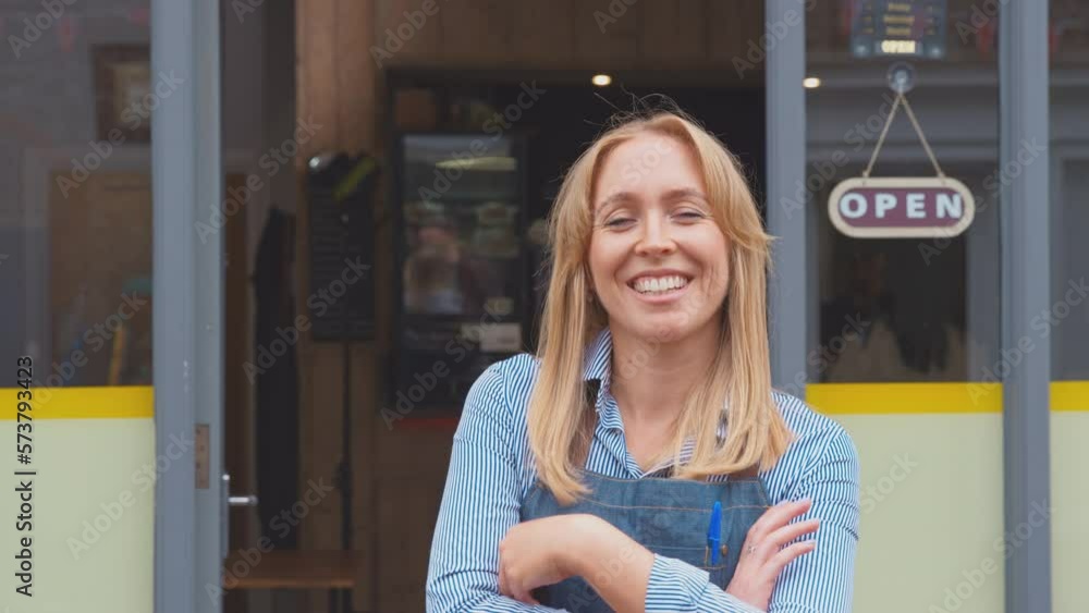 Portrait of woman working in shop or cafe standing in doorway next to open sign - shot in slow motion Portrait of woman working in shop or cafe standing in doorway next to open sign - shot in slow motion