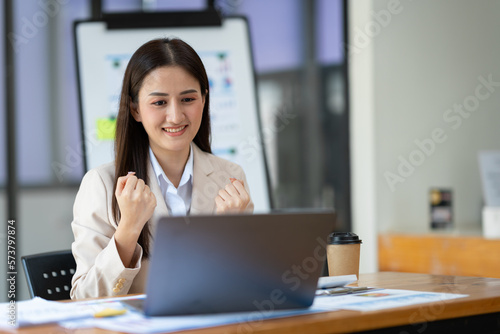 Beautiful asian businesswoman working with laptop computer expresses joy about successful business finance in real estate project Make a lot of profits in the office.