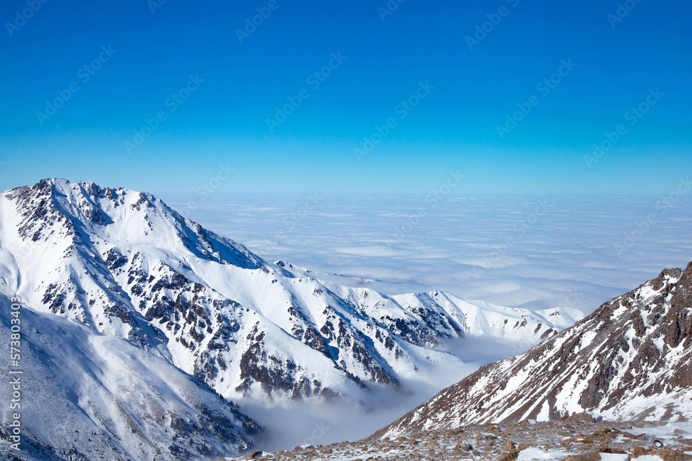 Obraz premium Beautiful landscape of winter mountains over clouds.