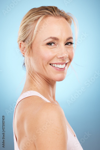 Skincare  woman and portrait in studio for beauty  dermatology and wellness cosmetics on blue background. Happy mature female model  facial and smile for aesthetic glow  botox transformation and face