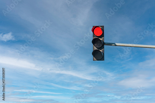 Modern traffic light with red light in front of cloudless sunny blue sky photo