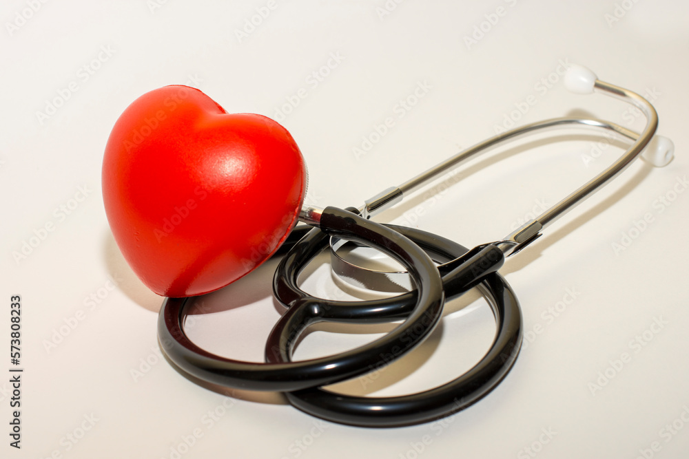 Selective focus of stethoscope on white surface with a red heart, medical concept Selective focus of stethoscope on white surface with a red heart, medical concept