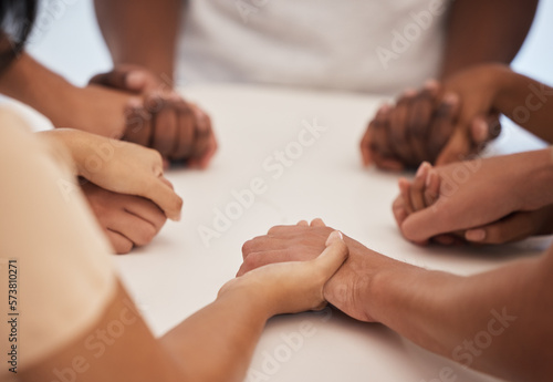 Holding hands, praying and people worship for peace, trust or faith in God at a table together. Pray, Christian and community by group hand in prayer, praise or blessing while united in Jesus Christ