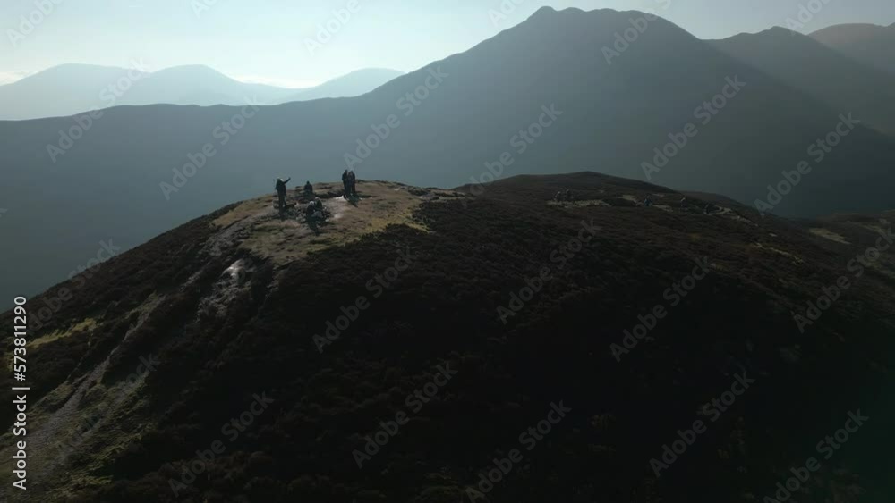Hikers on hilltop with orbit revealing misty mountains and orange bracken at Barrow Fell English Lake District Hikers on hilltop with orbit revealing misty mountains and orange bracken at Barrow Fell English Lake District