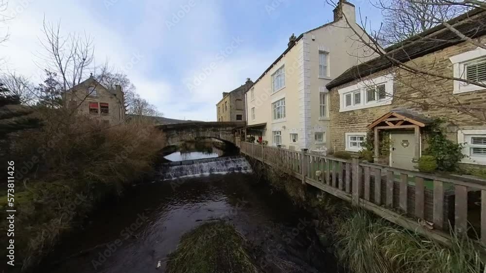 Small country waterfall flowing under a stone arch bridge. Small rural UK village. Small country waterfall flowing under a stone arch bridge. Small rural UK village.