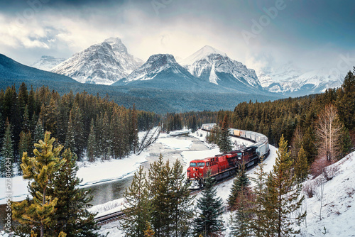 Morants Curve with iconic red cargo train passing through bow valley and rocky mountains in winter at Banff national park