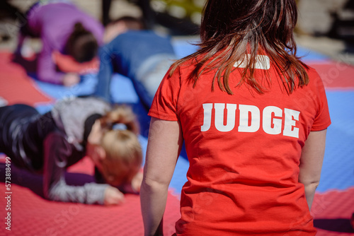 Back view of female judge in red shirt plank holding competition