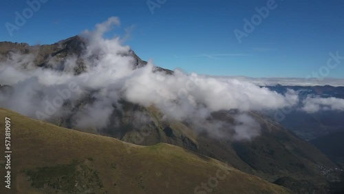 Mountains shrouded in clouds on sunny summer day, Col du Portet in France. Aerial panning and blue sky for copy space photo