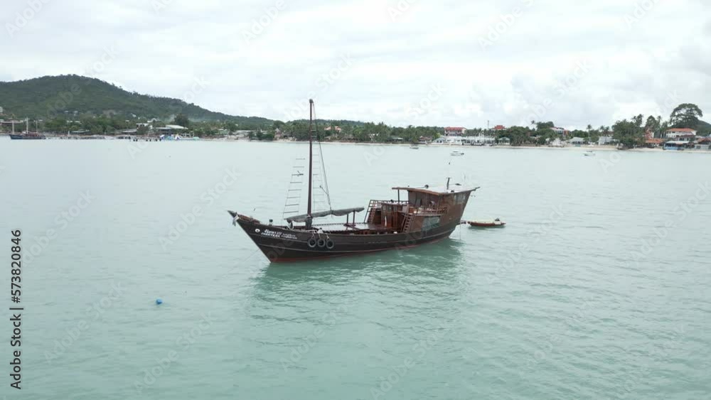 Aerial view circling large Thai fishing boat anchored offshore with dingy attached Aerial view circling large Thai fishing boat anchored offshore with dingy attached