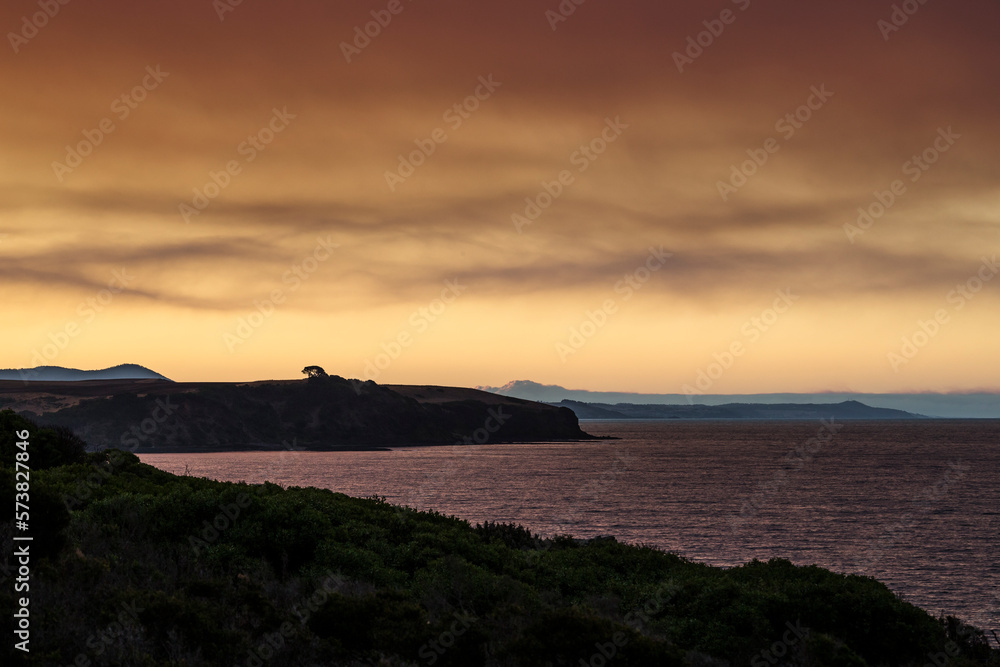 Coastal Tasmanian scenery with vibrant sunset and smokey sky. Coastal Tasmanian scenery with vibrant sunset and smokey sky.