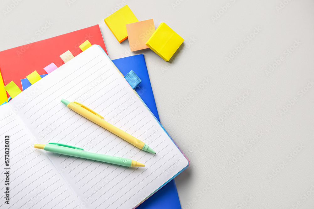 Notebooks, pens and sticky notes on light background, closeup Notebooks, pens and sticky notes on light background, closeup